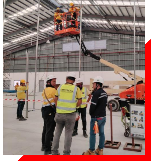 A group of men wearing safety vests and hard hats stands on a platform, engaged in a construction-related activity.