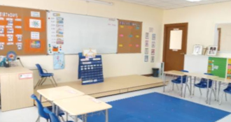 classroom featuring rows of desks and chairs, with a large whiteboard at the front for teaching purposes.