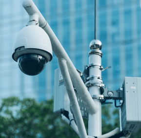 A security camera mounted on a pole overlooks a building, enhancing surveillance and safety in the area.