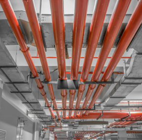 Red pipes are installed in a spacious building with white walls, creating a striking industrial contrast.