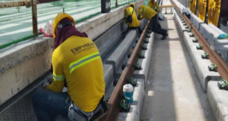 Workers in hard hats and safety vests are actively constructing a building at a busy construction site.