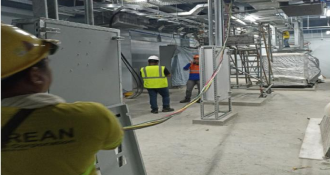 Workers in hard hats and safety vests are actively constructing a building at a busy construction site.